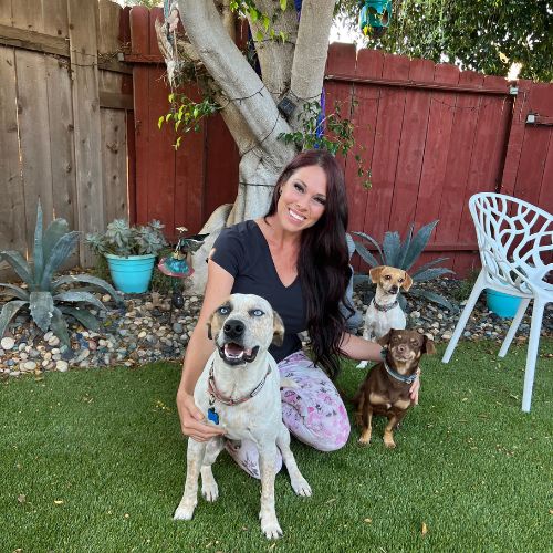 Jessica Wheatcraft smiling facing camera with two dogs