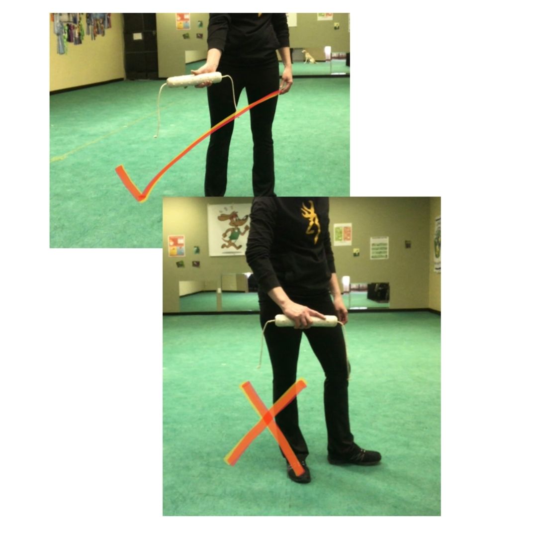 Two pictures comparing bumper holding positions. The first picture show the bumper being held with the handler's hand at the back, such that the full front of the bumper is visible. This is marked with a checkmark to show it is our desired holding position. The second picture shows the handler holding the bumper with their hand on the side nearest the camera or dog, and how the hand blocks the view. This is marked with an x because we don't want to hold the bumper this way. 
